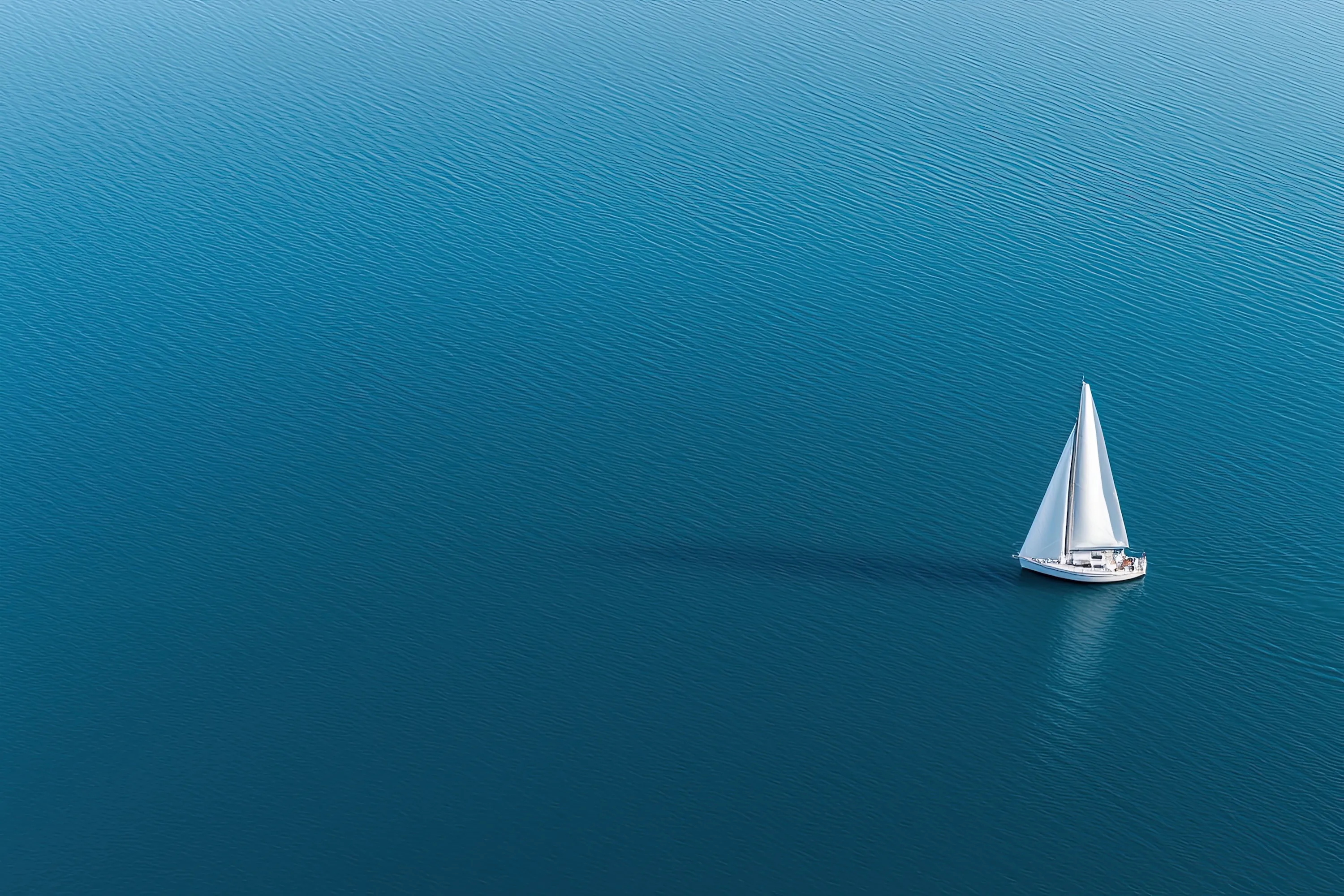 A white sailboat floating on top of a large body of water